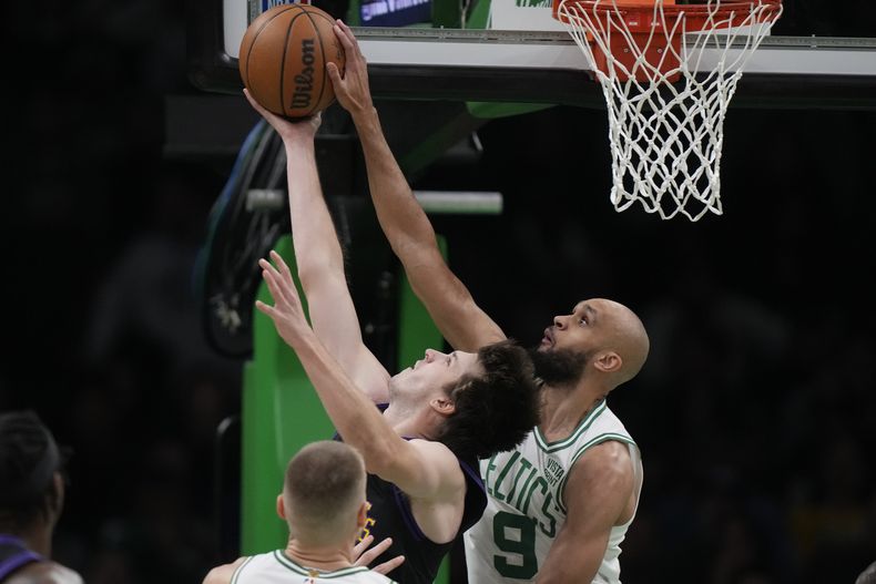 Austin Reaves, base de los Lakers de Los Ángeles, dispara frente a Derrick White, de los Celtics de Boston, en el partido del jueves 1 de febrero de 2024 (AP Foto/Steven Senne)