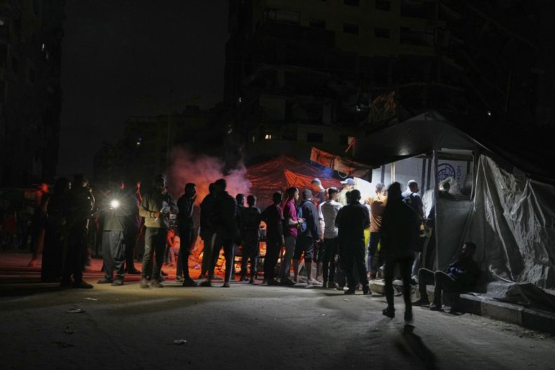 Palestinos hacen fila para comprar una cena en un puesto de comida cerca de la playa en un campamento de carpas para desplazados en el puerto de Ciudad de Gaza, el sábado 14 de junio de 2025. (AP Foto/Jehad Alshrafi)