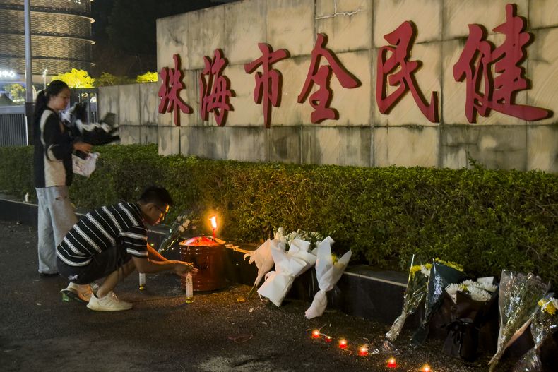 Un hombre enciende una vela cerca de unas flores colocadas en el exterior de la Plaza del Gimnasio Popular de Zhuhai, donde un hombre embistió deliberadamente con su coche a las personas que hacían ejercicio en el centro deportivo, matando a algunas e hiriendo a otras en Zhuhai, en la provincia meridional china de Guangdong, el martes 12 de noviembre de 2024. (AP foto/Ng Han Guan, archivo)