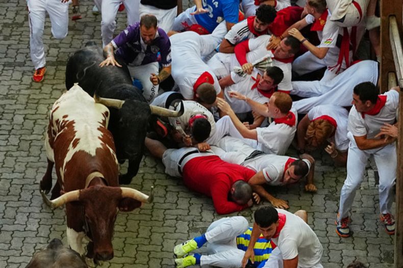 Corredores caen junto a un toro de lidia de la ganadería Jandilla durante el octavo encierro de las fiestas de San Fermín en Pamplona, España, el 14 de julio de 2026. (AP Foto/Miguel Oses)