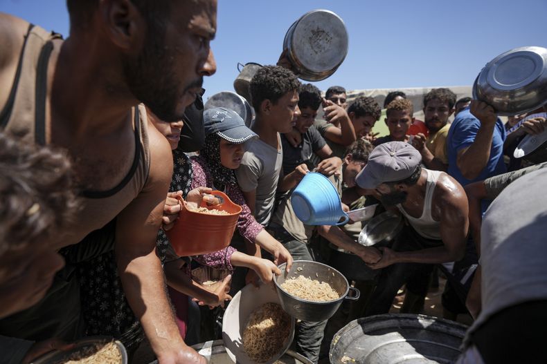 Palestinos desplazados esperan para recibir comida en Deir al Balah, en el centro de la Franja de Gaza, el 23 de agosto de 2024. (AP Foto/Abdel Kareem Hana)