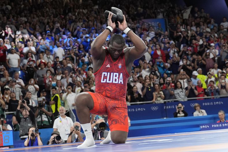 El cubano Mijaín López cuelga sus zapatillas tras derrotar al chileno Yasmani Acosta en la final de los 130 kilogramos de la lucha grecorromana de los Juegos Olímpicos de París, el martes 6 de agosto de 2024. (AP Foto/Eugene Hoshiko)