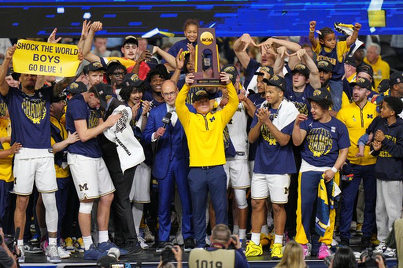 El entrenador de Michigan Dusty May sostiene el trofeo para celebrar el campeonato colegial al vencer en la final a UConn el lunes 6 de abril del 2026.(AP Foto/AJ Mast)