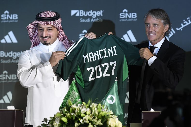 Roberto Mancini y Yasser Al Misehal, presidente de la Federación de Fútbol de Arabia Saudí, posan con la camiseta que le presentar a Mancini durante la conferencia de prensa para presentar al nuevo seleccionador el lunes 28 de agosto del 2023. (AP Foto)