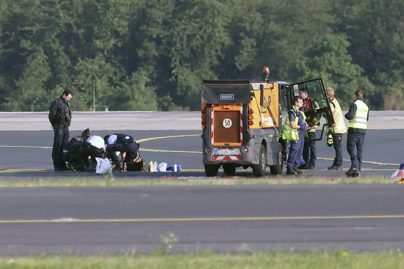Agentes de policía y personal de seguridad se ven de pie en un aeropuerto y tratan de despegar a activistas del grupo Last Generation que se habían pegado al asfalto en la zona del aeropuerto en Düsseldorf, Alemania, el jueves 13 de julio de 2023. (David Young/dpa via AP)