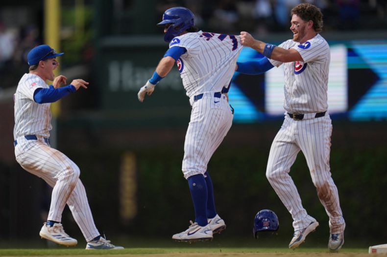 Dansby Swanson de los Cachorros de Chicago, al centro, celebra con Carson Kelly, a la derecha, y Matt Shaw después de impulsar la carrera de la victoria en la décima entrada de un juego de béisbol contra los Filis de Filadelfia, el jueves 23 de abril de 2026, en Chicago. (AP Foto/Erin Hooley)