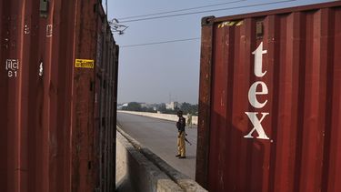 Un policía monta guardia en una carretera cortada con contenedores de mercancías antes de una protesta de partidarios del encarcelado ex primer ministro Imran Khan para exigir su liberación, en Peshawar, Pakistán, el domingo 11 de octubre de 2026. (AP Foto/Mohammad Zubair)