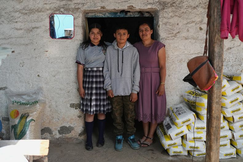 Mirsy Maricela Alva López, a la derecha, y sus hijos, Ederson, en el centro, y Briseidy posan para fotos en su casa en San Martín Cuchumatán, Guatemala, el jueves 30 de abril de 2026. (AP Foto/Moisés Castillo)