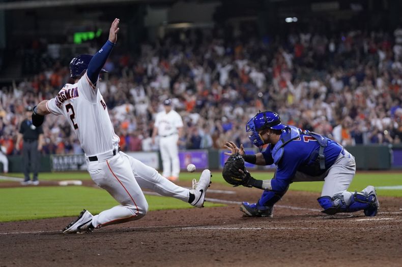 Alex Bregman, de los Astros de Houston, anota la carrera de la victoria frente al cátcher brasileño Yan Gomes, de los Cachorros de Chicago, el miércoles 17 de mayo de 2023 (AP Foto/David J. Phillip)