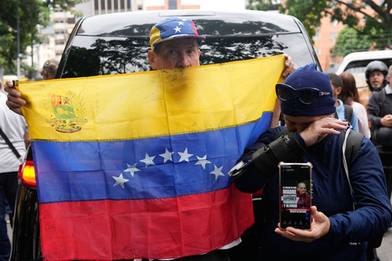 Un hombre sostiene una bandera venezolana en Caracas, Venezuela, el martes 19 de mayo de 2026, durante el velorio de Carmen Navas, madre de Víctor Hugo Quero, quien, según las autoridades, falleció bajo custodia tras su detención aproximadamente un año antes. (AP Foto/Ariana Cubillos)
