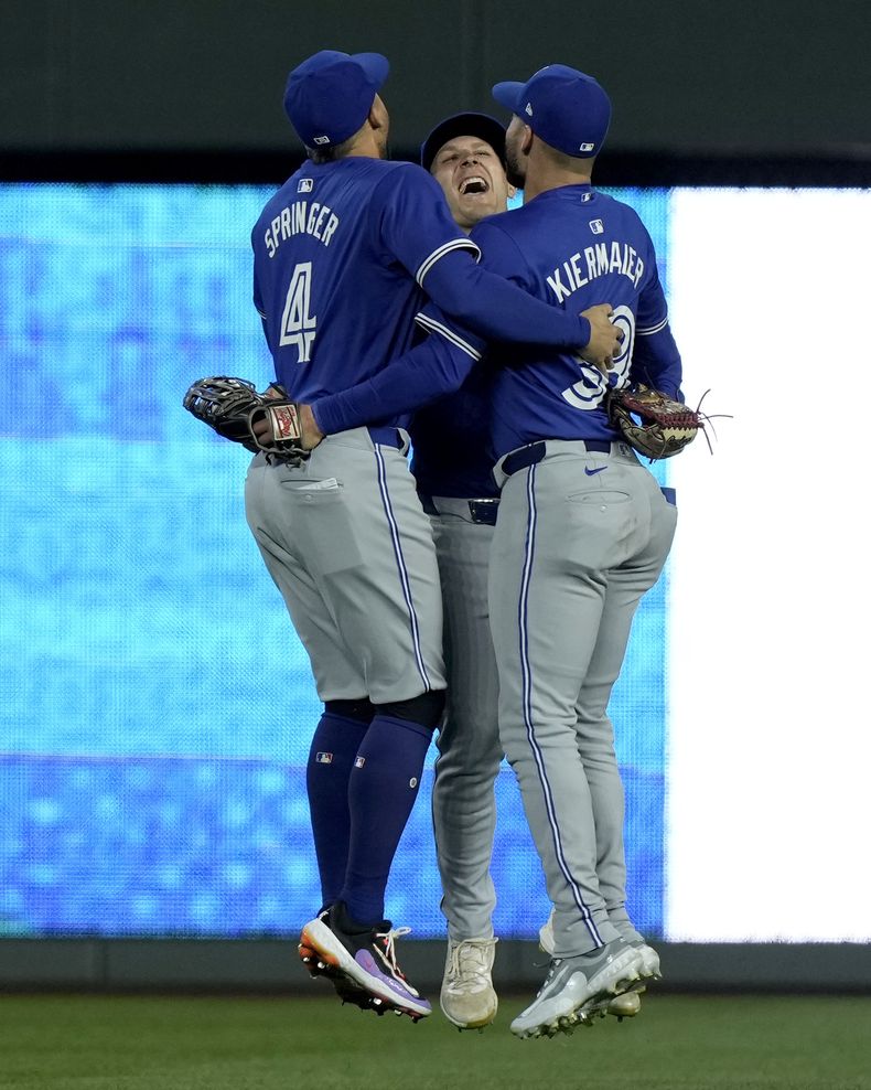 Los jardineros de los Azulejos de Toronto, Daulton Varsho, centro, Kevin Kiermaier, derecha, y George Springer (4) celebran después de su juego de béisbol contra los Reales de Kansas City, el lunes 22 de abril de 2024, en Kansas City, Missouri. Los Azulejos ganaron 5-3. (AP Foto/Charlie Riedel)