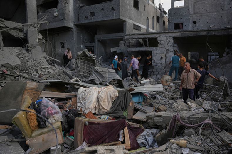 Palestinos recorren un edificio destruido por un bombardeo israelí, en Jan Yunis, sur de la Franja de Gaza, el 9 de octubre de 2026. (Foto AP/Abdel Kareem Hana)