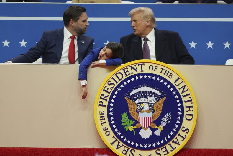 El vicepresidente JD Vance, izquierda, el presidente Donald Trump, derecha, y el hijo de Vance, Vivek, miran un desfile bajo techo por la investidura presidencial, el lunes 20 de enero de 2025, en Washington. (AP Foto/Matt Rourke)
