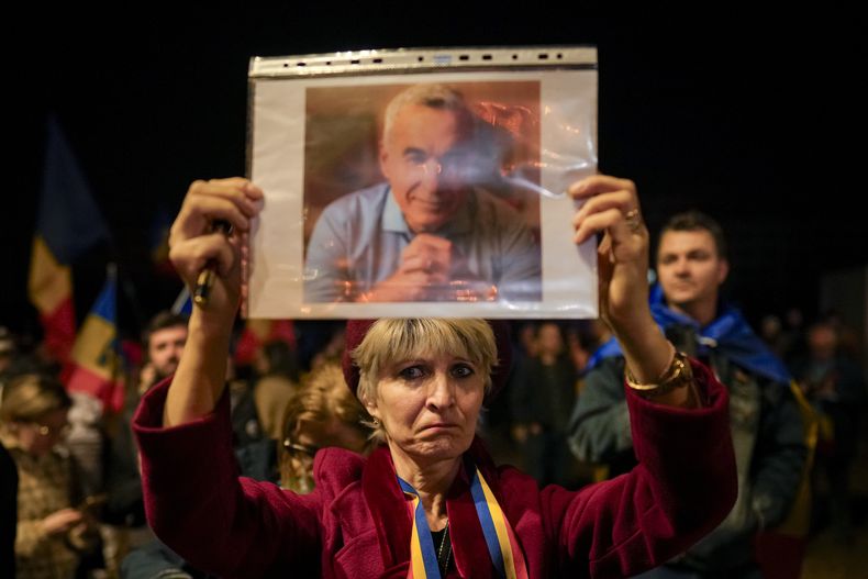 Una mujer muestra un retrato de Calin Georgescu en una protesta después de que el Tribunal Constitucional de Rumania mantuviera la anulación de su candidatura en la repetición de la elección presidencial, en Bucarest, Rumania, el martes 11 de marzo de 2025. (AP Foto/Vadim Ghirda)