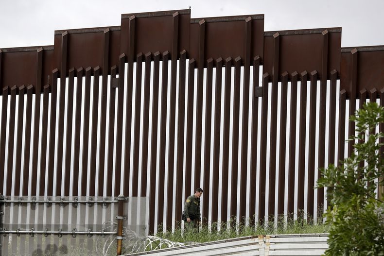 ARCHIVO - Un agente de la Patrulla Fronteriza de EEUU camina junto a una valla que separa a Tijuana, México, de San Diego, en San Diego, el 18 de marzo de 2020. (AP Foto/Gregory Bull, Archivo)