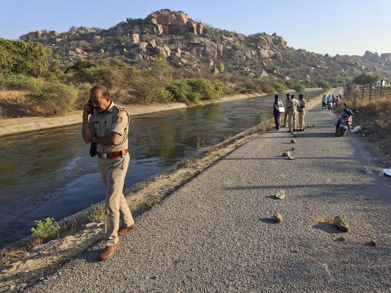 Un policía habla por teléfono en la escena del crimen durante la búsqueda de los viajeros que fueron empujados al canal por tres hombres acusados de violar en grupo a dos mujeres, en el distrito de Koppal, en el estado de Karnataka, en el sur de India, el viernes 7 de marzo de 2025. (AP Foto)