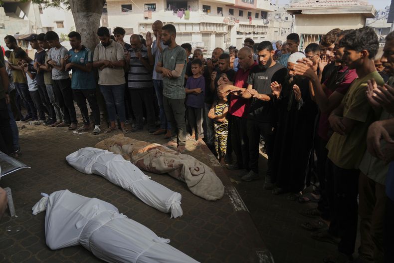 Palestinos rezan junto a los cuerpos de familiares muertos en un ataque aéreo israelí en la Franja de Gaza, durante su funeral en el exterior de la morgue del hospital de Shifa, en la Ciudad de Gaza, el 26 de julio de 2025. (AP Foto/Abdel Kareem Hana)