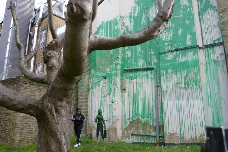 Una mujer mira un nuevo mural de Banksy en una pared en Londres, el lunes 18 de marzo de 2024. Un nuevo mural de Banksy en el vecindario de Finsbury Park atrajo multitudes a una calle de Londres el lunes, incluso antes de que el esquivo artista de graffiti confirmara que la obra era suya.(Foto AP/Alastair Grant)