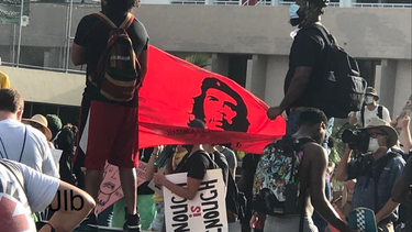 manifestantes levantan bandera del che guevara en una protesta en el downtown de miami