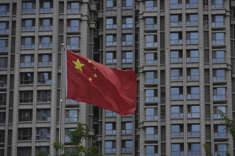 Una bandera nacional china ondea junto a un edificio residencial en Beijing, el lunes 16 de junio de 2025. (AP Foto/Andy Wong)