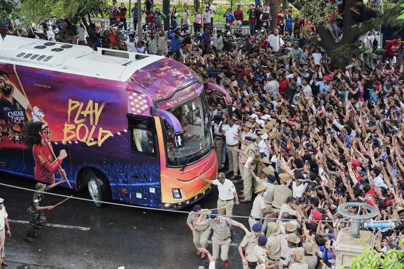 Aficionados aplauden cuando el autobús que transporta a los jugadores de críquet del Royal Challengers Bengaluru, ganadores de la Premier League india, llega al estadio M. Chinnaswamy en Bangalore, India, el miércoles 4 de junio de 2025. (AP Foto/Aijaz Rahi)