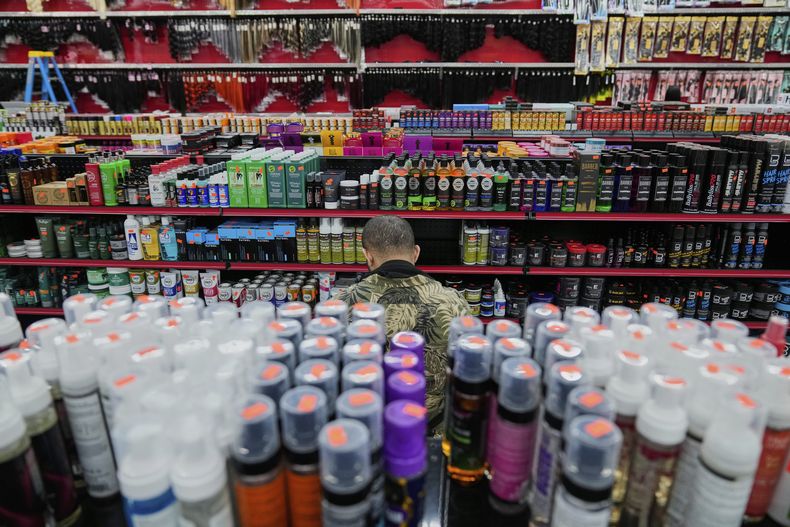 Un empleado de Seven Daughters, una tienda de productos de belleza en College Park, Georgia, está rodeado de productos mientras reabastece los estantes, el martes 6 de mayo de 2025. (AP Foto/Stephanie Scarbrough)