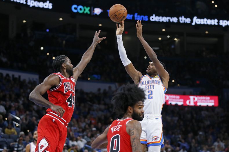 Shai Gilgeous-Alexander (2), del Thunder de Oklahoma City, tira sobre la marca defensiva de Patrick Williams, de los Bulls de Chicago, cerca de Coby White (0), durante la primera mitad del juego de baloncesto de la NBA, el miércoles 22 de noviembre de 2023, en Oklahoma City. (AP Foto/Nate Billings)