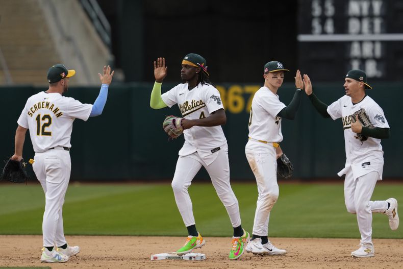 El jardinero derecho de los Atléticos de Oakland, Lawrence Butler, segundo desde la izquierda, celebra con el campocorto Max Schuemann (12) después de su victoria sobre los Gigantes de San Francisco el sábado 17 de agosto de 2024, en Oakland, California (AP Foto/Godofredo A. Vásquez)