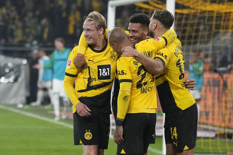 Julian Brandt, izquierda, es felicitado por sus compañeros del Borussia Dortmund luego de anotar el primer gol en el partido de la Liga Alemana ante el Werder Bremen, en Dortmund, Alemania, el viernes 20 de octubre de 2023. (AP Foto/Martin Meissner)