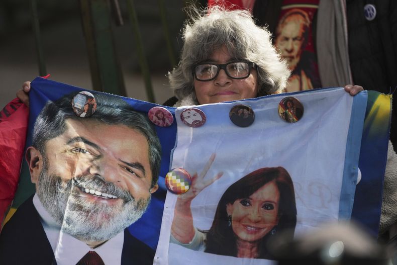 Una simpatizante de la expresidenta argentina Cristina Fernández sostiene una bandera en la que la dirigente peronista está retratada junto al presidente de Brasil, Luiz Inácio Lula da Silva, en las inmediaciones de su vivienda donde cumple prisión domiciliaria por la condena de seis años de cárcel por corrupción, en Buenos Aires, Argentina, el jueves 3 de julio de 2025 (AP Foto/Rodrigo Abd).