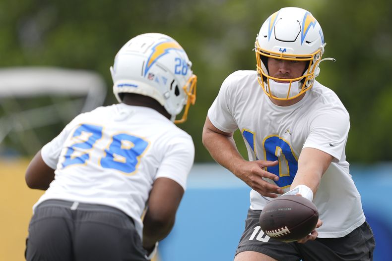 El quarterback de los Chargers de Los Ángeles Justin Herbert realiza un ejercicio con el corredor Isaiah Spiller durante una práctica del equipo el martes 4 de junio del 2024. (AP Foto/Ryan Sun)