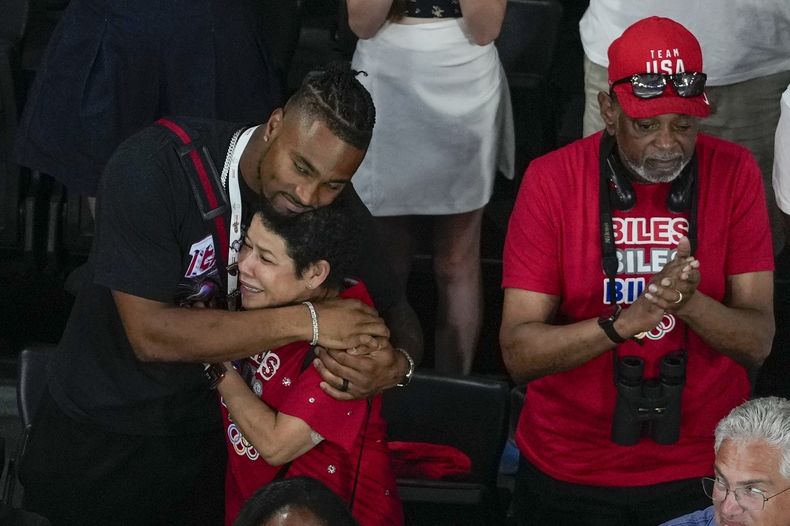 Jonathan Owens, esposo de la gimnasta de los Estados Unidos, Simone Biles, abraza a su madre Nellie Biles, mientras es condecorada con la medalla de oro durante las finales del all-around de la Gimnasia Artística Femenina, en el Bercy Arena, en París, Francia. (AP Foto/Morry Gash)