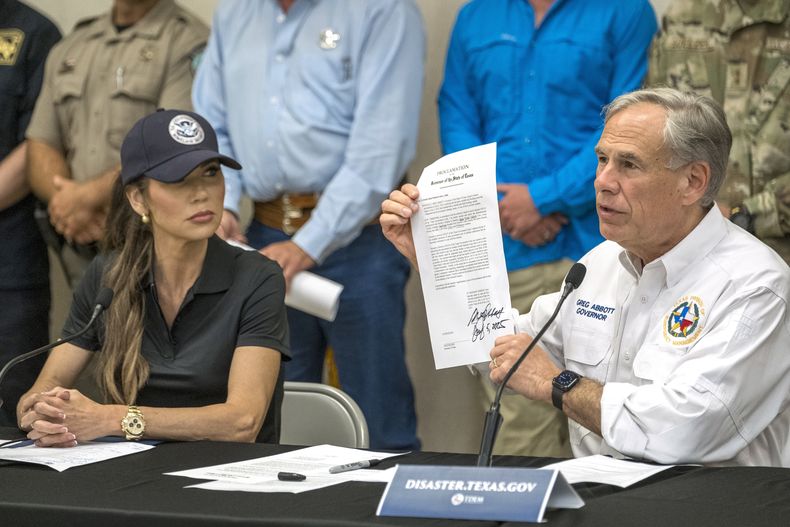 El gobernador de Texas, Greg Abbott, sostiene una declaración de desastre recién firmada, junto a la secretaria de Seguridad Nacional, Kristi Noem, a la izquierda, durante una conferencia de prensa sobre las recientes inundaciones a lo largo del río Guadalupe, el sábado 5 de julio de 2025 en Kerrville, Texas. (AP Foto/Rodolfo Gonzalez)