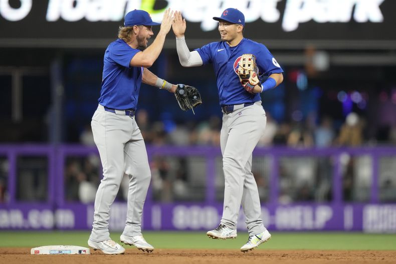 Patrick Wisdom, de los Cachorros de Chicago, a la izquierda, choca los cinco con Seiya Suzuki, a la derecha, después de un partido contra los Marlins de Miami, el sábado 24 de agosto de 2024, en Miami. (AP Foto/Lynne Sladky)