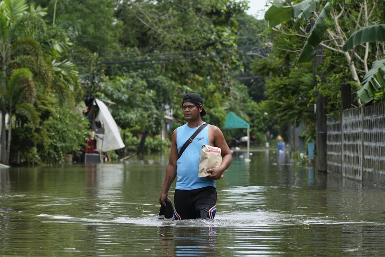 Un residente camina por una calle inundada tras el paso de la tormenta tropical Trami, el 25 de octibre de 2024, en Cainta, en la provincia filipina de Rizal. (AP Foto/Aaron Favila)
