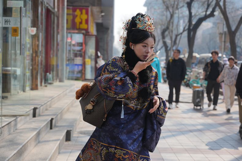 Una mujer vestida con un traje tradicional chino habla por teléfono en las calles de Beijing el sábado 4 de abril de 2026. (AP Foto/Ng Han Guan)