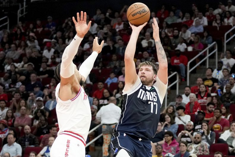 Luka Doncic (77), de los Mavericks de Dallas, dispara con la presión defensiva de Dillon Brooks, de los Rockets de Houston, durante la primera mitad del juego de baloncesto de la NBA, el domingo 31 de marzo de 2024, en Houston. (AP Foto/Eric Christian Smith)