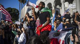 Un hombre grita a través de un megáfono fuera del Ayuntamiento de la ciudad durante las protestas por las redadas de inmigración, el miércoles 11 de junio de 2025, en Los Ángeles. (AP Foto/Ethan Swope)