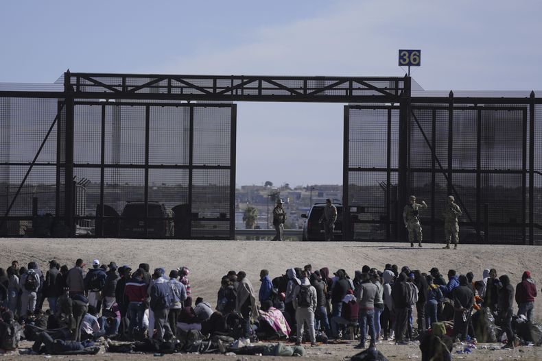 Migrantes que cruzaron la frontera desde México hacia Estados Unidos esperan a un costado del muro fronterizo en donde agentes de la Patrulla Fronteriza de Estados Unidos montan guardia, el 30 de marzo de 2023, en una imagen tomada desde Cuidad Juárez, México. (AP Foto/Fernando Llano, Archivo)