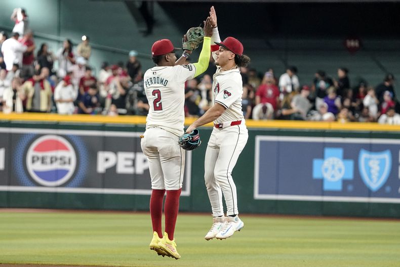 El dominicano Geraldo Perdomo y Alek Thomas de los Diamondbacks de Arizona celebran la victoria ante los Padres de San Diego el domingo 29 de septiembre del 2024. (AP Foto/Darryl Webb)