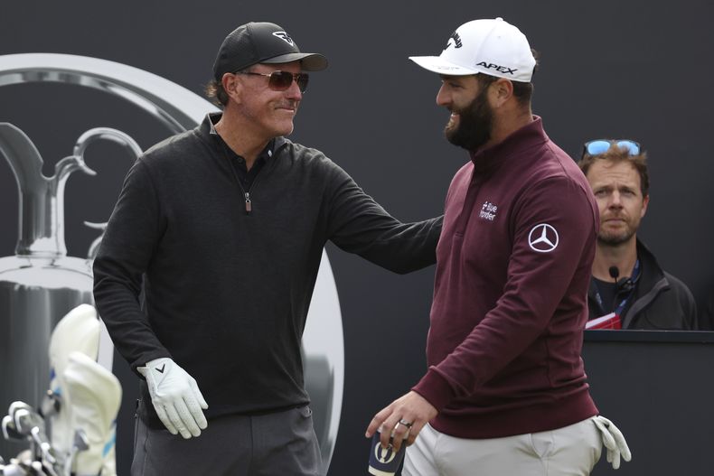 ARCHIVO - El golfista español Jon Rahm saluda al estadounidense Phil Mickelson en el primer tee durante una ronda de práctica para el Abierto Británico de golf, en Hoylake, Inglaterra. (AP Foto/Peter Morrison)