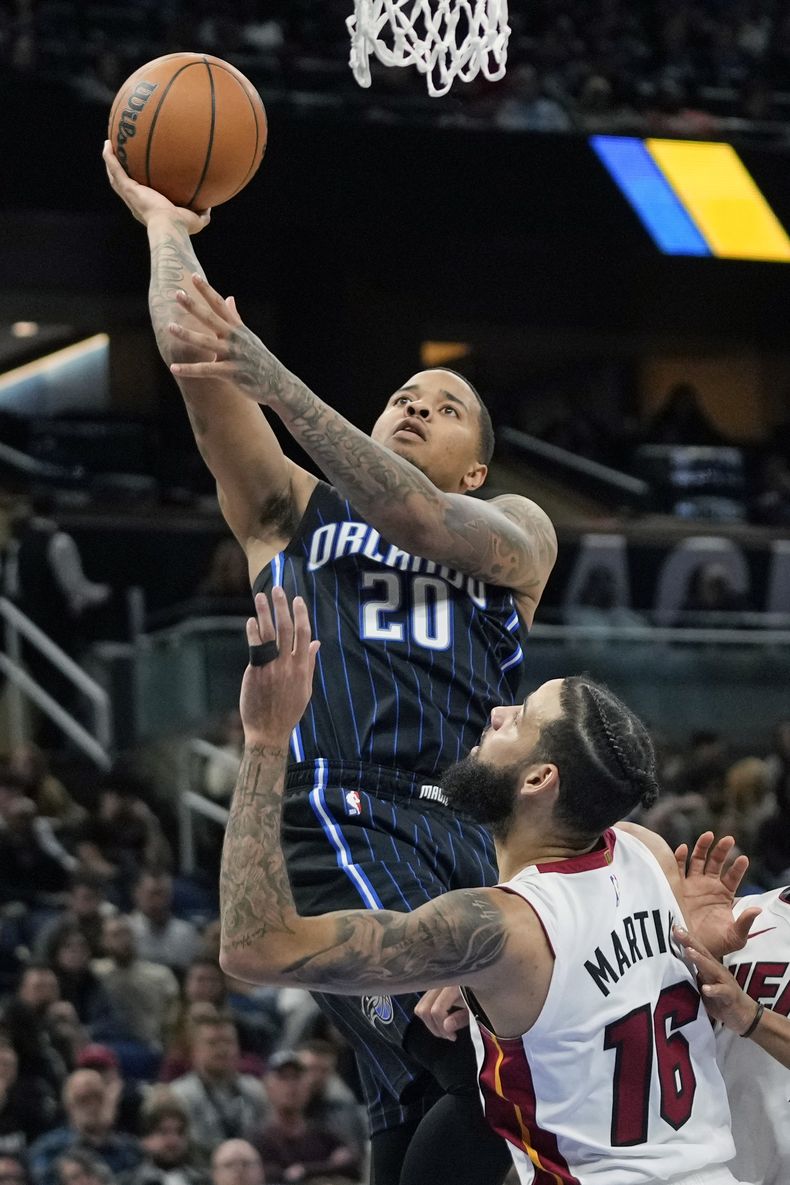 El escolta del Magic de Orlando Markelle Fultz (20) dispara sobre el alero del Heat de Miami Caleb Martin (16) durante la segunda mitad del partido de baloncesto de la NBA el domingo 21 de enero de 2024 en Orlando, Florida (AP Foto/John Raoux)