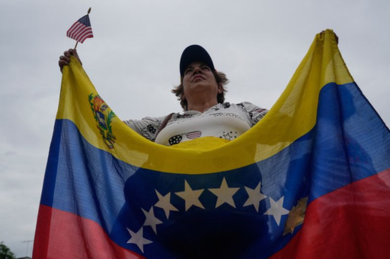 Una mujer sostiene una bandera estadounidense en miniatura y una bandera nacional venezolana durante una protesta que exige elecciones presidenciales y salarios justos, en la plaza Alfredo Sadel de Caracas, Venezuela, el jueves 16 de abril de 2026. (Foto AP/Ariana Cubillos)