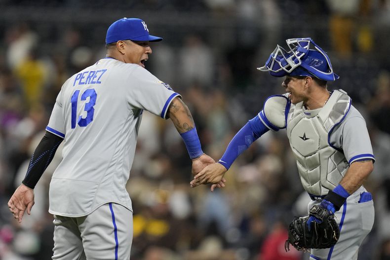 El venezolano Salvador Pérez, bateador designado de los Reales de Kansas City, festeja con su compatriota Freddy Fermín, tras el triunfo sobre los Padres de San Diego, el martes 16 de mayo de 2023 (AP Foto/Gregory Bull)