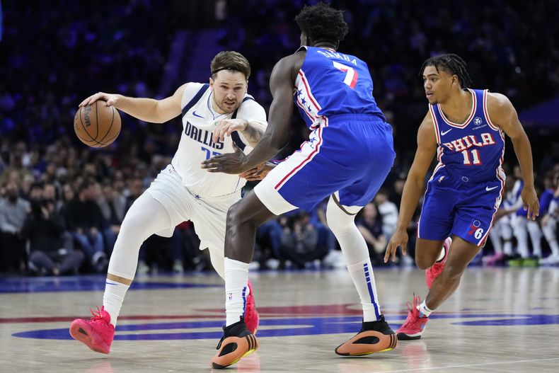 Luka Doncic, izquierda, de los Mavericks de Dallas, trata de pasar a Mo Bamba (7) y Jaden Springer (11), de los Sixers de Filadelfia, durante la priimera mitad del juego de baloncesto de la NBA, el lunes 5 de febrero de 2024, en Filadelfia. (AP Foto/Matt Rourke)
