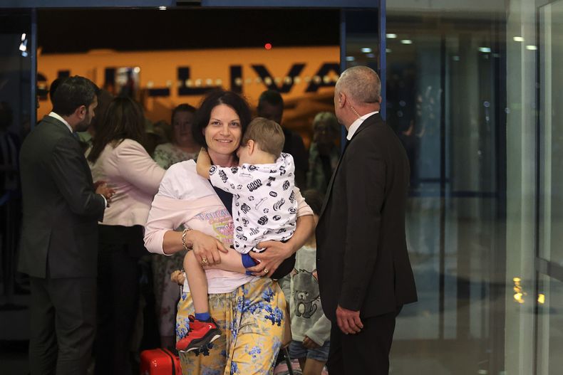 Una madre carga a su hijo mientras el primer grupo de ciudadanos búlgaros evacuados desde Israel, llega al aeropuerto Vassil Levsky de Sofía, junto con decenas de ciudadanos extranjeros de Eslovenia, Estados Unidos, Bélgica, Albania, Kosovo y Rumania, el miércoles 18 de junio de 2025. (AP Foto/Valentina Petrova)
