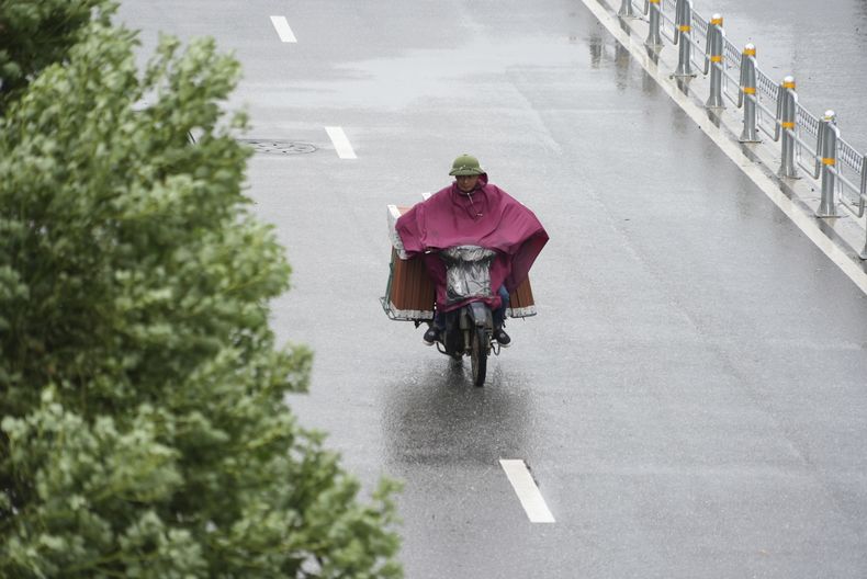 Una persona maneja una motocicleta bajo la lluvia provocada por la tormenta tropical Wipha en Hanói, Vietnam, el martes 22 de julio de 2025. (AP Foto/Hau Dinh)