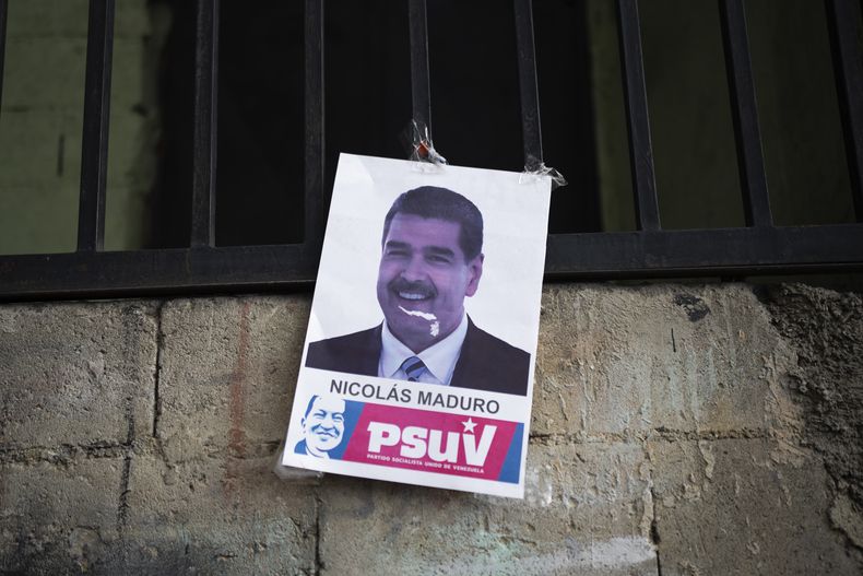Un cartel del presidente de Venezuela Nicolás Maduro, con el rostro del difunto mandatario Hugo Chávez en la parte inferior, cuelga en el exterior de una residencia en el vecindario de Catia, el miércoles 5 de junio de 2024, en Caracas. (AP Foto/Ariana Cubillos)