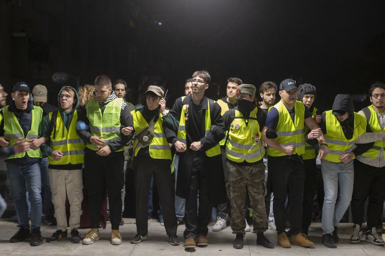 Estudiantes forman una cadena humana mientras bloquean el acceso al edificio de la televisora estatal RTS en el centro de Belgrado, Serbia, el lunes 10 de marzo de 2025. (AP Foto/Marko Drobnjakovic)