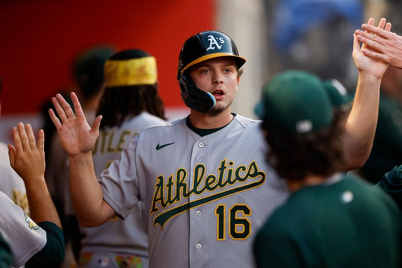 Nick Kurtz (16), de los Atléticos, es recibido por sus compañeros de equipo tras anotar gracias a un sencillo de Shea Langeliers (23) durante la quinta entrada de un partido de béisbol contra los Angelinos de Los Ángeles, el viernes 26 de junio de 2026, en Anaheim, California. (Foto AP/Caroline Brehman)